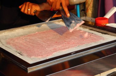 Asya heyecan pişirme süreci spatula ile rulo dondurma meyve ve krema donmuş Pan kızarmış. Bulanık hareket el ve yaparken spatula. Seçici odak