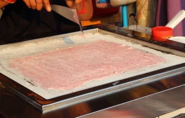 Asya heyecan pişirme süreci rulo dondurma meyve ve krema soğutulmuş Pan kızarmış. Organik doğal haddelenmiş dondurma. Bulanık hareket el ve yaparken spatula. Seçici odak