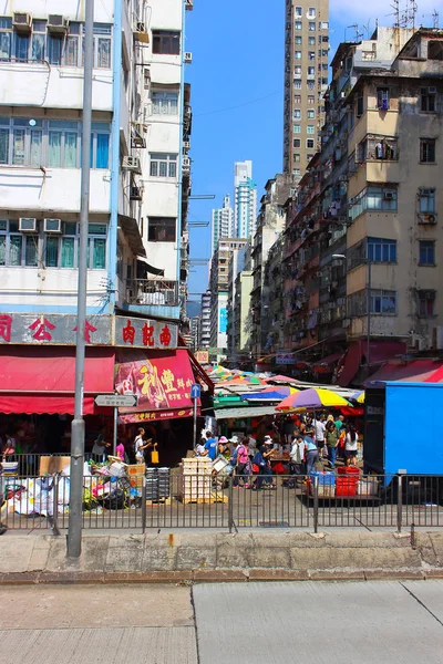 中国香港 0月7日 7日上午 亚洲街头市场位于老可怕的摩天大楼之间的一条狭窄街道上 彩色屋顶遮阳伞摊位 路上的购物者和垃圾的人群 — 图库照片