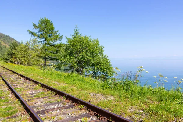 Rails of the Trans-Siberian Railway on the shore of Baikal Lake going into the distance. Summer on Circum-Baikal Railroad.