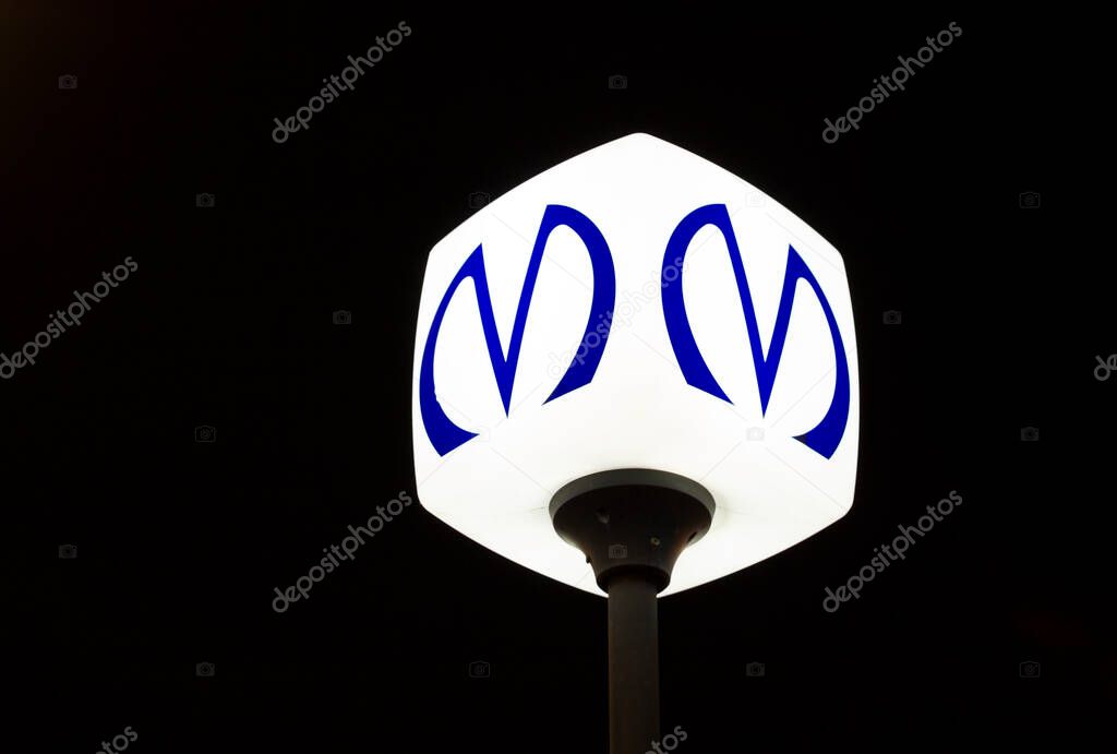 St. Petersburg, Russia - January 5, 2020: Glowing emblem sign of metro in Saint Petersburg on dark background. Installed in front of the metro station