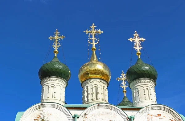 Gold domes Orthodox church brilliant in the sun. Crosses of the white Orthodox church on the background of bright blue sky in summer day, Zaraysk, Russia
