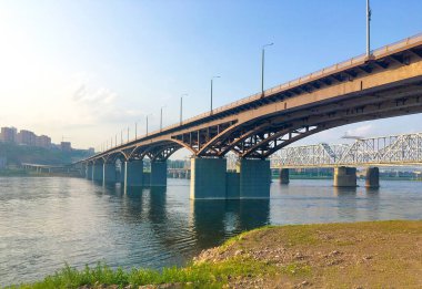 Rusya, Krasnoyarsk 'taki Yenisei Nehri' nden geçen karayolu köprüsü ve demiryolu köprüsü manzaralı. Şehir yaz manzarası. Seçici odak, bulanık arkaplan.
