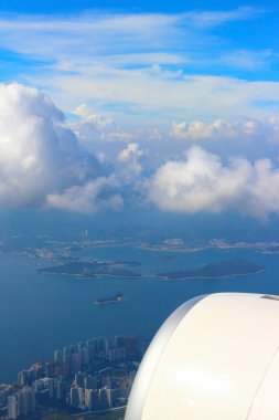 Uçan uçaktan Hong Kong adaları üzerindeki hava manzarası. Gökyüzü, bulut ve denizdeki küçük gemiler bir araya geldi. Seyahat için harika bir geçmiş. Seçici odak