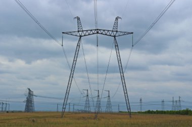 Yüksek voltajlı elektrik hatlarının endüstriyel arka planı. Elektrik direkleri alan boyunca kesişiyor.