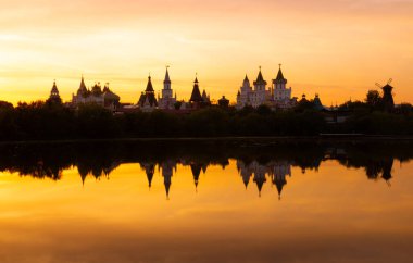 Izmailovsky Kremlin 'in Moskova, Rusya' daki göl suyundaki bulanık yansıması üzerine portakal rengi gün batımı. Sıcak renklerde Rus manzarası