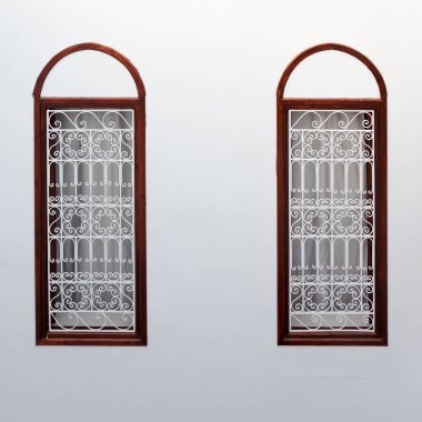 Beyaz duvarda dekoratif kafesle süslenmiş iki dar pencere. Marakeş 'teki Medina Mahallesi için Fas otantik iç mimarisi