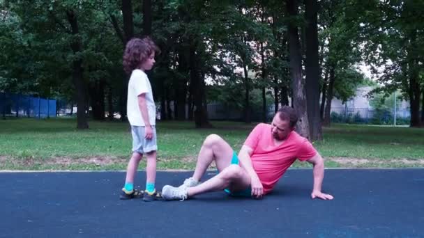 A son helping his father to rise to his feet on a sorcery site. — Stock Video