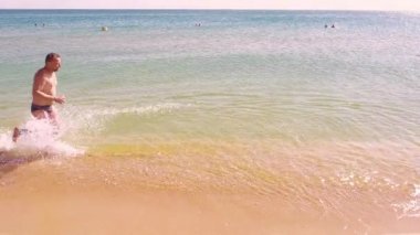 Deniz kenarı boyunca çalışan mutlu bir aile. Ağır çekim.