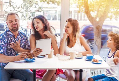 Kahvaltı ve tablet kullanarak mutlu bir aile. Mutlu bir adam ve çocukları seyir perde için istimal enterne, gülümseyen kafe, dijital tablet olan büyük bir şirket online satın