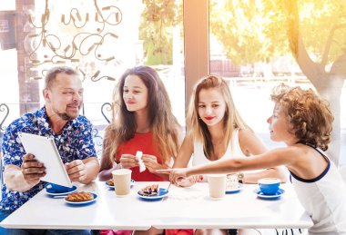 Kahvaltı ve tablet kullanarak mutlu bir aile. Mutlu bir adam ve internet, kullanarak seyir perde için üç çocukları gülümseyen kafe, dijital tablet olan büyük bir şirket online satın