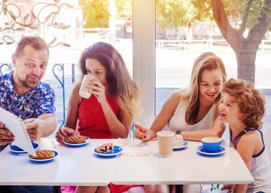 Kahvaltı ve tablet kullanarak mutlu bir aile. Mutlu bir adam ve internet, kullanarak seyir perde için üç çocukları gülümseyen kafe, dijital tablet olan büyük bir şirket online satın