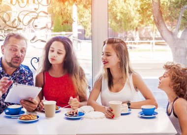 Kahvaltı ve tablet kullanarak mutlu bir aile. Mutlu bir adam ve internet, kullanarak seyir perde için üç çocukları gülümseyen kafe, dijital tablet olan büyük bir şirket online satın