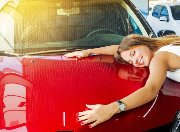 Araba hakkında hayal. Yeni kırmızı araba bayilik içinde başlık üzerinde sarılma muhteşem gülümseyen kadın yatıyor.