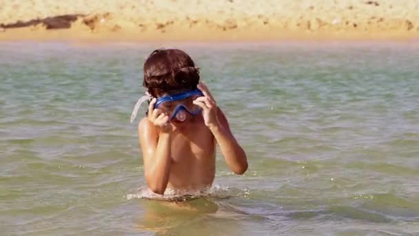 スキューバ ダイビング マスクでカーリーを探してかなりの少年は 水の中にダイブします スローモーション — ストック動画