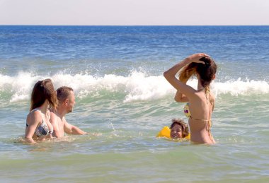 Dalgalar halinde oynarken dostça büyük aile kız. Sandy Beach shoreline alıştırma dalgalar ile