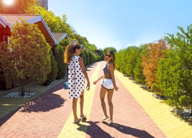 Tropikal tatil Bungalov ile lüks bir otel üzerinde yürüyen iki güzel esmer kız kardeş
