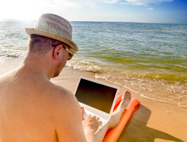 Deniz kenarında güzel yeri dizüstü bilgisayar kullanan adam