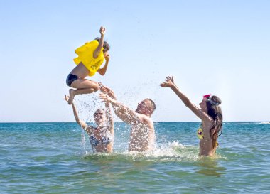 Baba ve kızı oğlu bir şişme can yeleği denizin içinde yukarı atar. Samimi ve mutlu aile kavramı