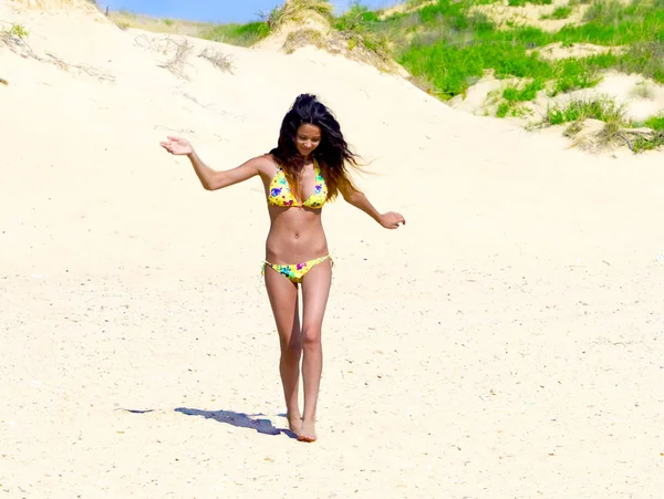 Sakin ve mutlu yüz ifadesi ile sahilde yürüyen güzel genç kadın