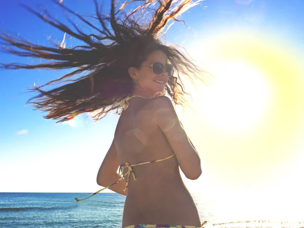 Güzel romantik kız açık havada. Güzel Model parlak güneşin arka planda bir tropik sahil üzerinde sarı bir mayo içinde. Uzun saçları rüzgarda. Arkadan aydınlatmalı, sıcak renk tonları