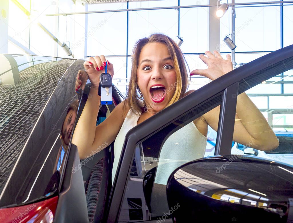 Young excited happy woman near the white car with keys in hand