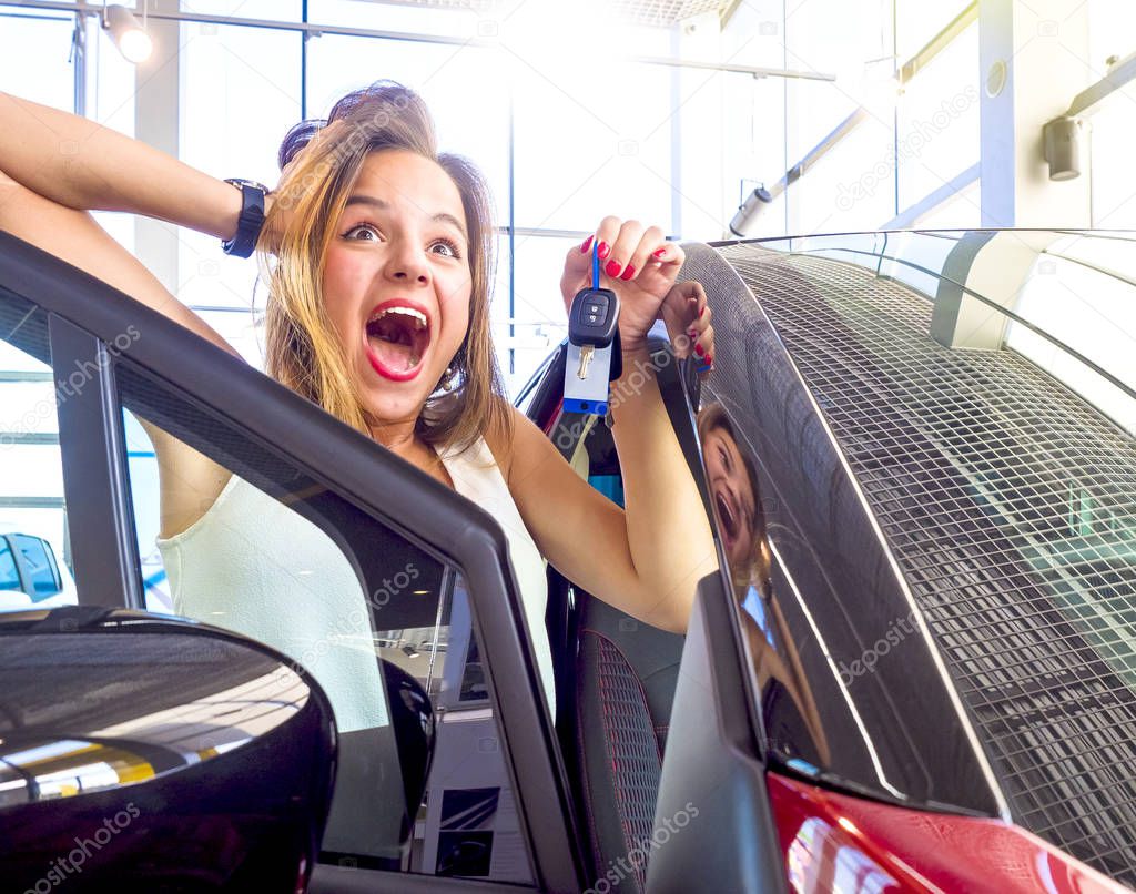 Young excited happy woman near the white car with keys in hand