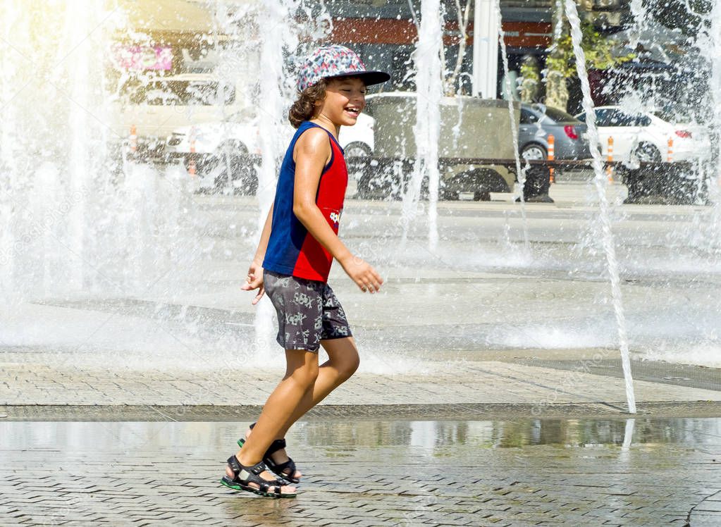 Happy kid playing in a fountain with water