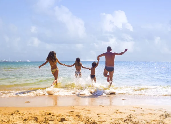 快乐的年轻家庭在海滩上玩得很开心 跑进温暖的大海 爱情和亲情的概念 — 图库照片