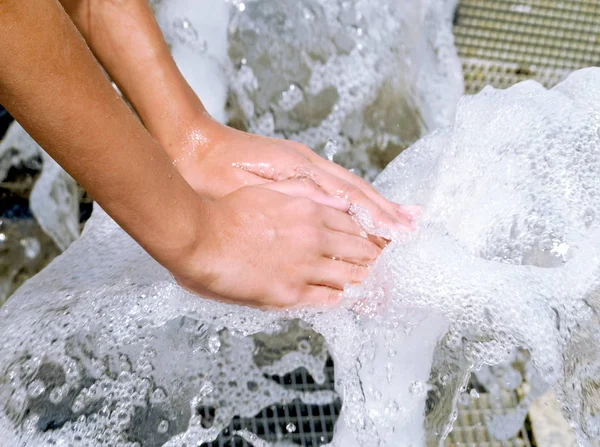 Hands touch the fountain. A stream of water from the fountain is touched by hands. Freshness and coolness concept