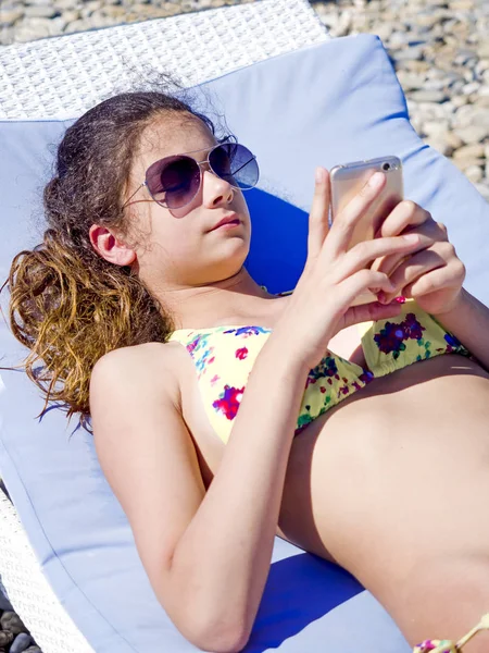 Young Woman with frustrated look sunbathing on lounger and using mobile phone. Discontent and disappointment concept