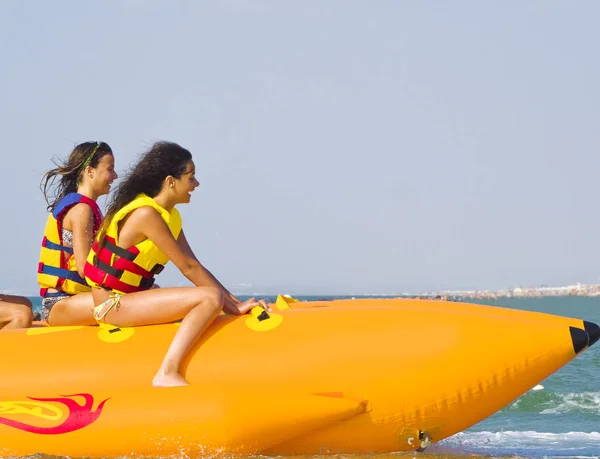 Sea 魅力の極端なスピードの魅力 日当たりの良い夏の日に乗ってバナナ ボートを楽しんでいる若者のグループです ビーチのウォーター スポーツ — ストック写真