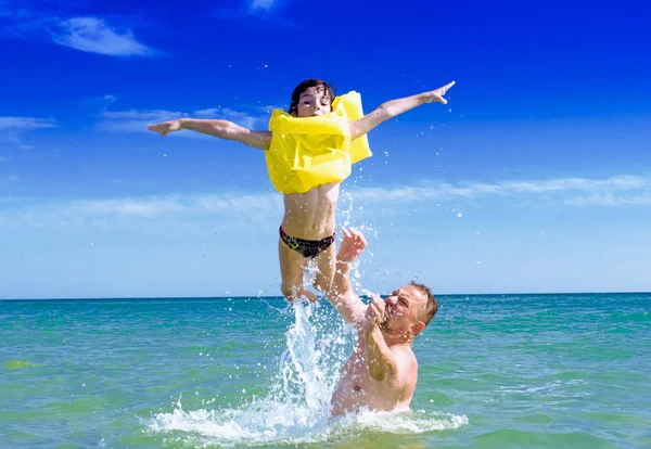 Gelukkig vader zoon gooien in de zee. Zoon vliegen over het water. — Stockfoto