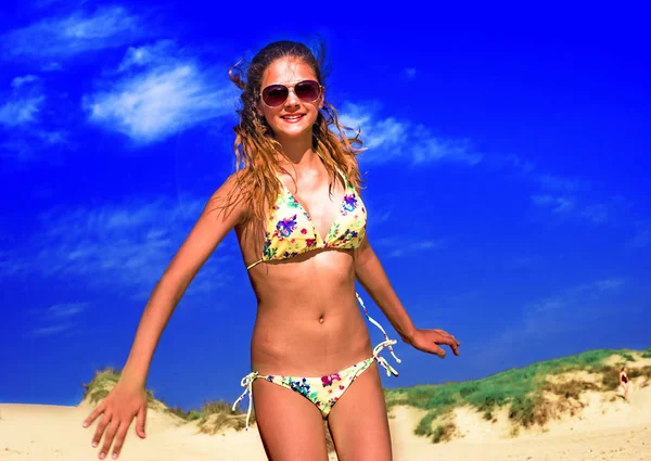 Vacker ung kvinna promenader på stranden med en lugn och glad ansikte uttryck — Stockfoto