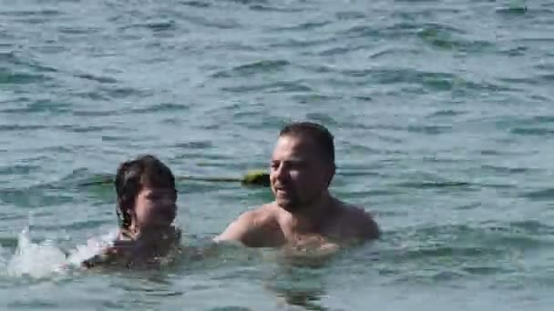 Vater und Sohn ruhen sich auf dem Meer aus. Papa bringt Sohn das Schwimmen bei. — Stockvideo