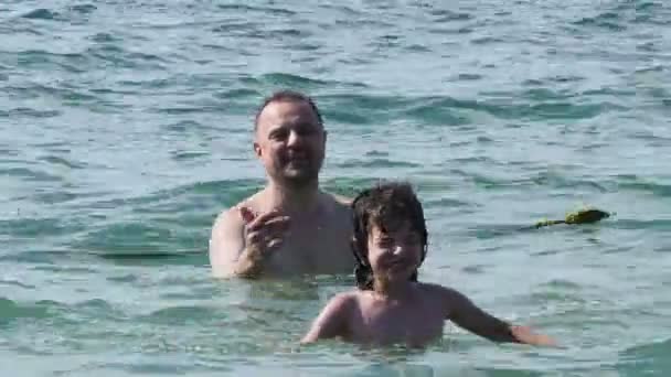 Papá e hijo están descansando en el mar. Papá enseña a su hijo a nadar. . — Vídeos de Stock