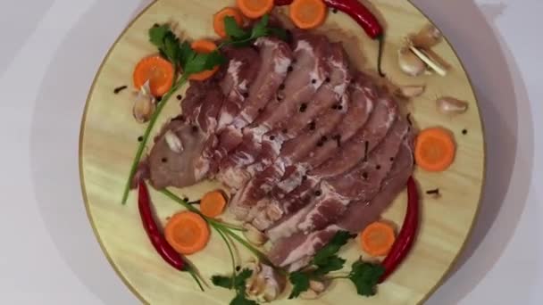 Fette fresche di carne, carote e spezie ruotano su un piatto di legno . — Video Stock