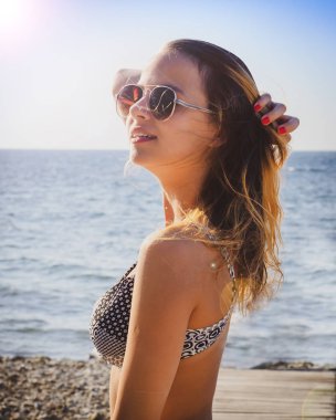 Sahilde mutlu bir kadın. Güzel kız yakın deniz arka plan üzerinde portresi. Sahilde bahar portre. Genç güzel kız. Genç gülümseyen kadın açık havada dikey. Kapatın. okyanus