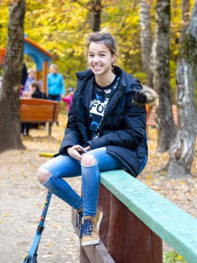 Çekici kız ekşitmeden sonbahar ormanın içinde. Güneşli bir günde bir Ahşap korkuluk-sonbahar bir parkta oturan bir genç portresi.