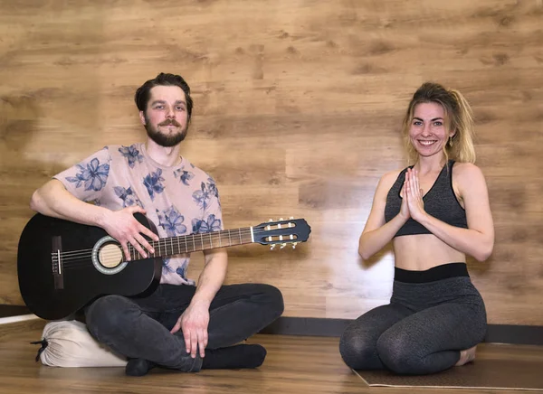 Newlyweds yoga meditation. Man playing guitar, woman doing asana exercises.