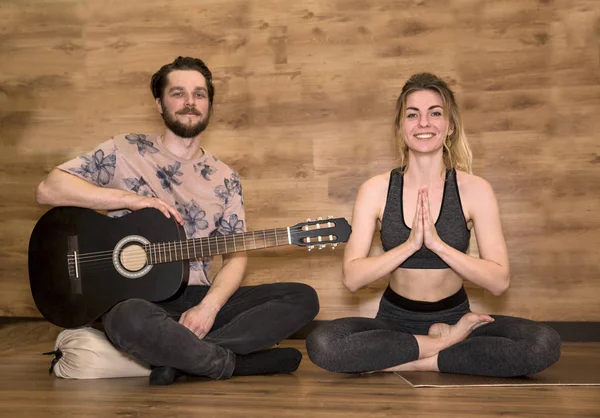 Newlyweds yoga meditation. Man playing guitar, woman doing asana exercises.