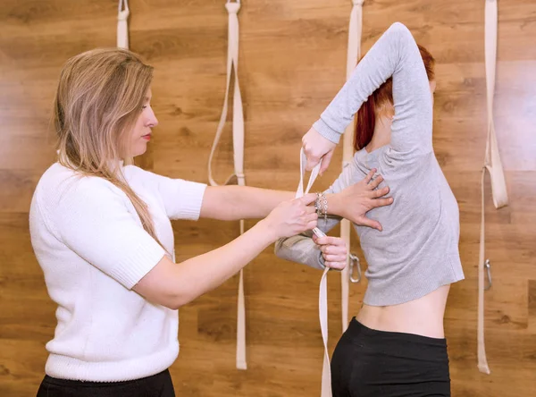 A yoga guru teaches a student yoga exercises.