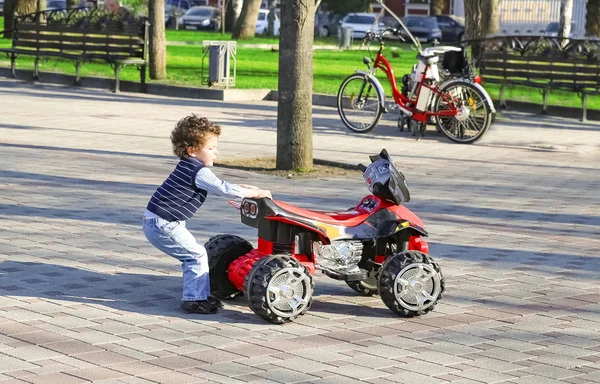 Freizeitpark, ein lustiger Junge zieht sein Spielzeugauto an einem sonnigen Sommertag — Stockfoto