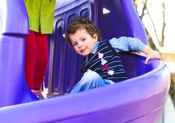 Boy having fun sliding down on the playground. kid playing outdoors. copy space for your text — Stock Photo, Image