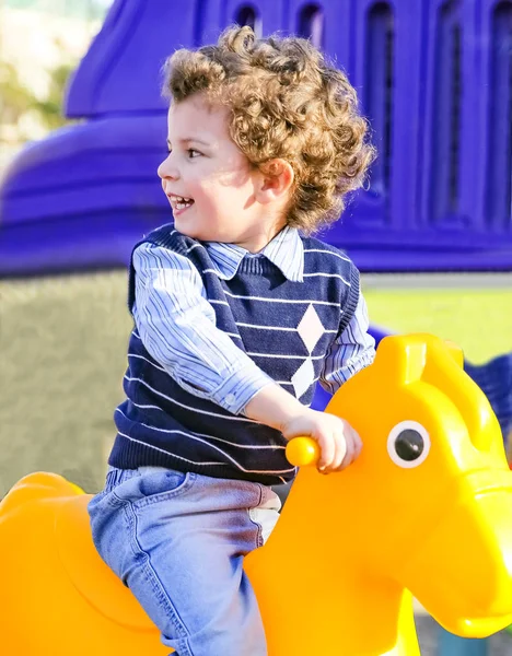 Three year old baby is swinging on a cockhorse on the playground. — Stock Photo, Image