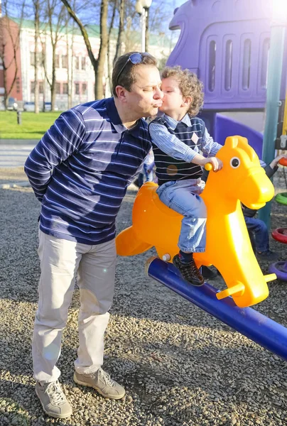 Father and son having fun on swing at playground in park — Stock Photo, Image