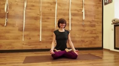 Padmasana asana gülümseyen yogi. Sevimli kadın lotus yoga poz uygulamaları. Çapraz ayaklı ahşap duvar arka plan üzerinde oturan genç bayan. Barışçıl, farkındalığı, meditasyon kavramları, ağır çekim