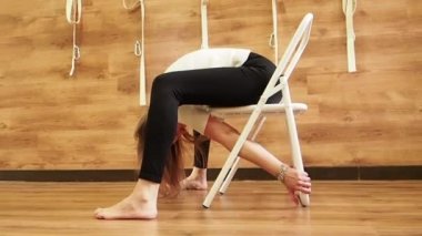 Studio ahşap duvarlar ve zemin ile pratik yoga öğretmeni. Yogi sandalye için parsvottanasana poz kullanarak. Duruş, yavaş yardım etmek Iyengar yoga eğitmeni ile sandalye pervane gibi