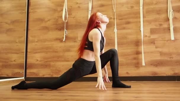 Joven mujer atractiva practicando yoga haciendo sus manos, Splits Pose, Monkey Pose en toda su longitud, sobre un fondo de estudio de madera, cámara lenta — Vídeo de stock