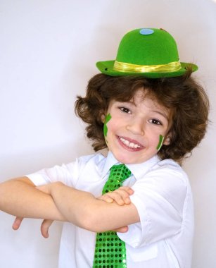 İspanyol çocuk çocuk eğleniyor Saint Patrick kutlamalar sırasında hafif bir arka plan üzerinde. Yanağımın üstünde Yeşil yonca ve İrlanda bayrağı bir çocuk gülümsüyorum. Aziz Patrick günü kutlamaları.